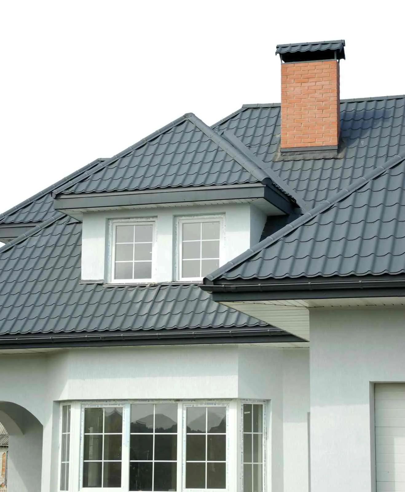 Roofer standing on the ridge of a brick house checking the shingles